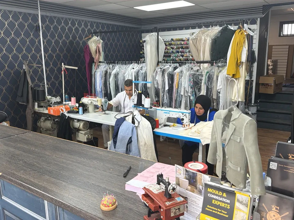 View over the counter into the Best Stitch workroom, with the team working at sewing machines